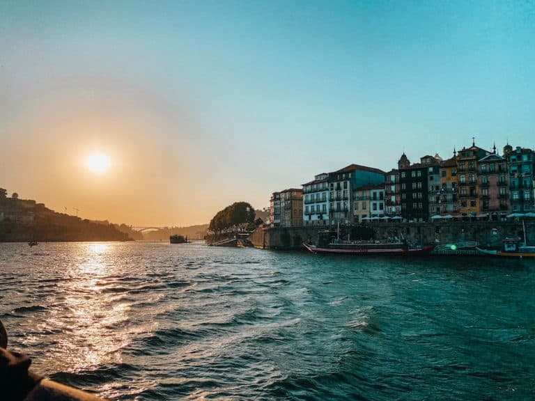Douro River at sunset with houses on the shoreline; view of one of the boat tours in Porto