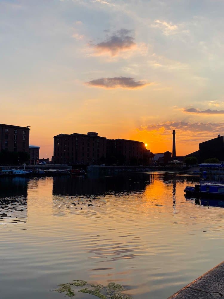 Sunset at the docks in Liverpool, buildings are reflected in the water