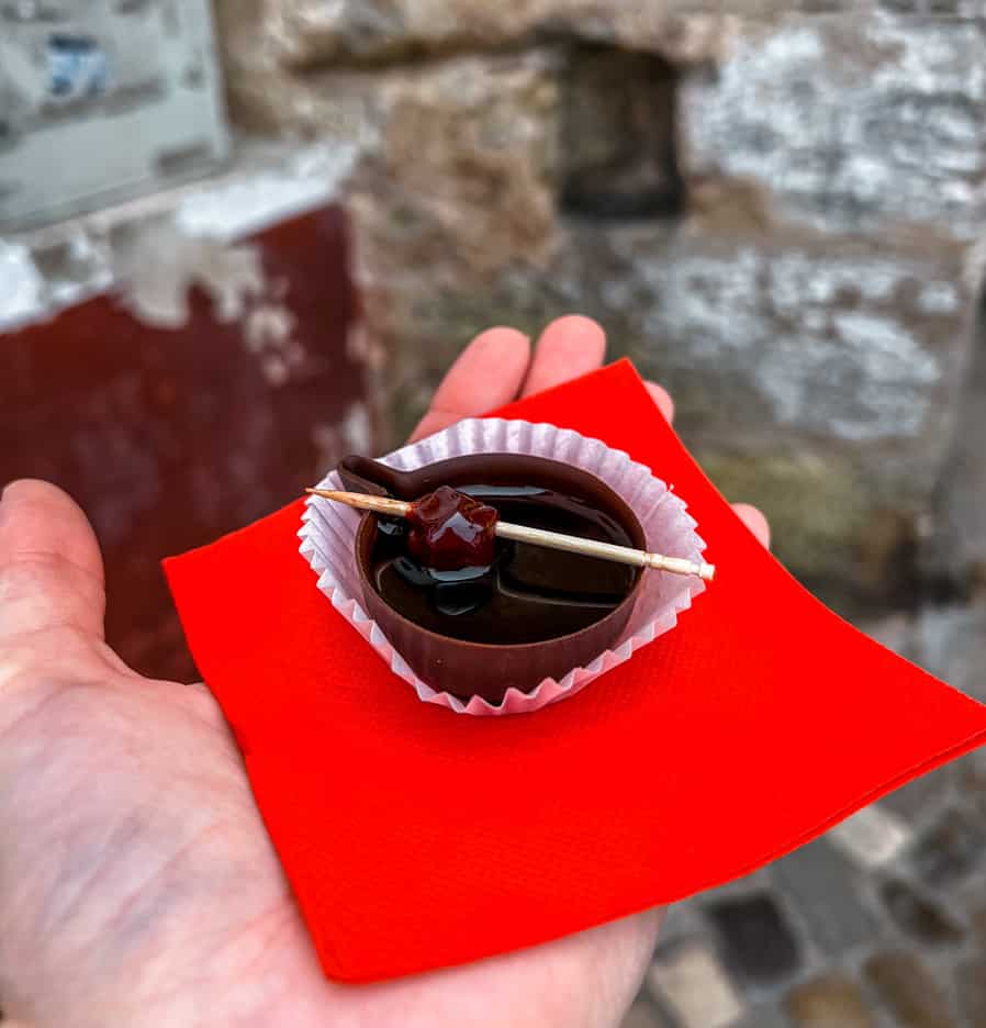 Hand holding a red tissue and a chocolate cup with cherry liquor in it