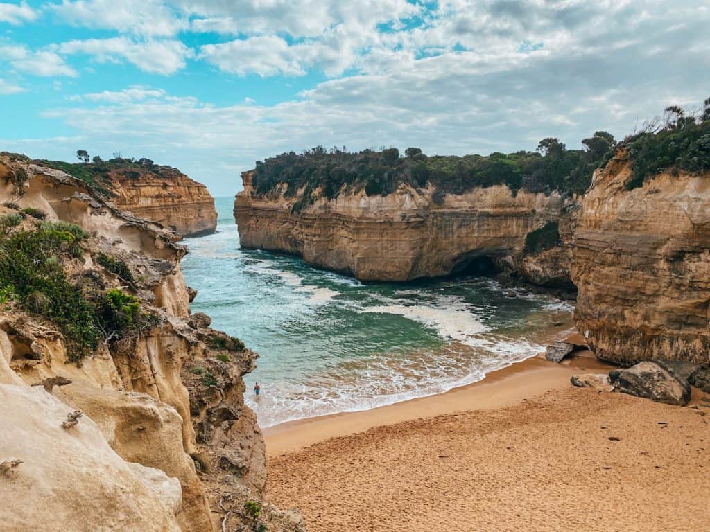 A sandy beach surrounded by cliffs and the ocean only has a small entrance; you can see this on a day trip to great ocean road from Melbourne