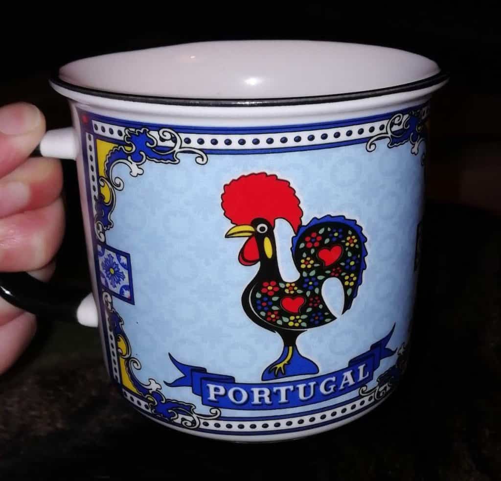 Hand holding a cup with a rooster on it