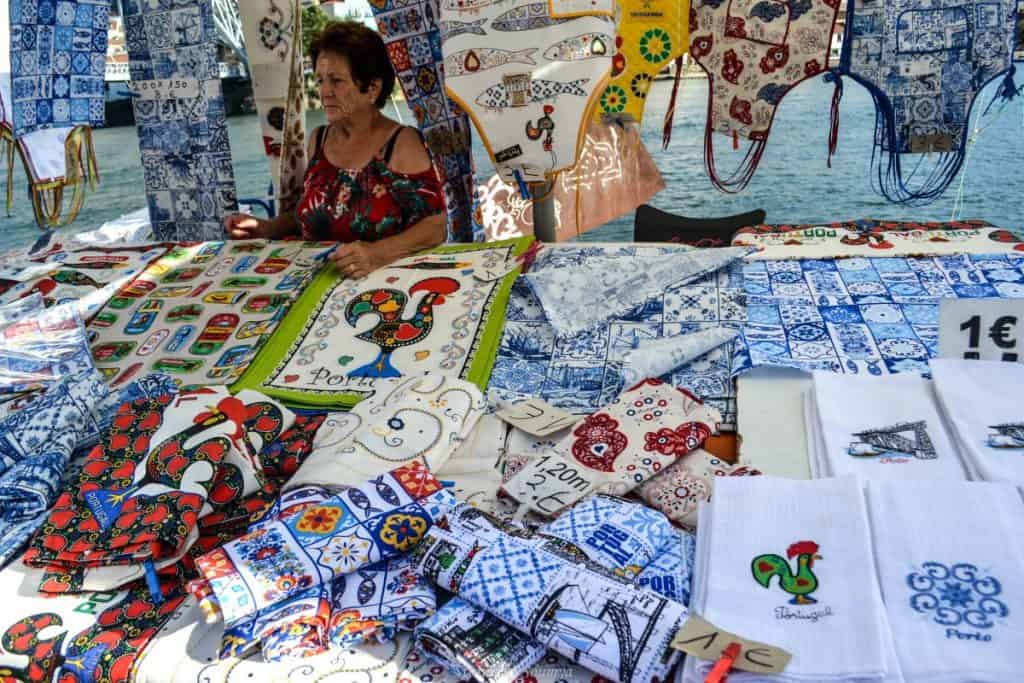 A market stall with an old woman selling embroidered towels and tea towels, which make for great souvenirs from Portugal