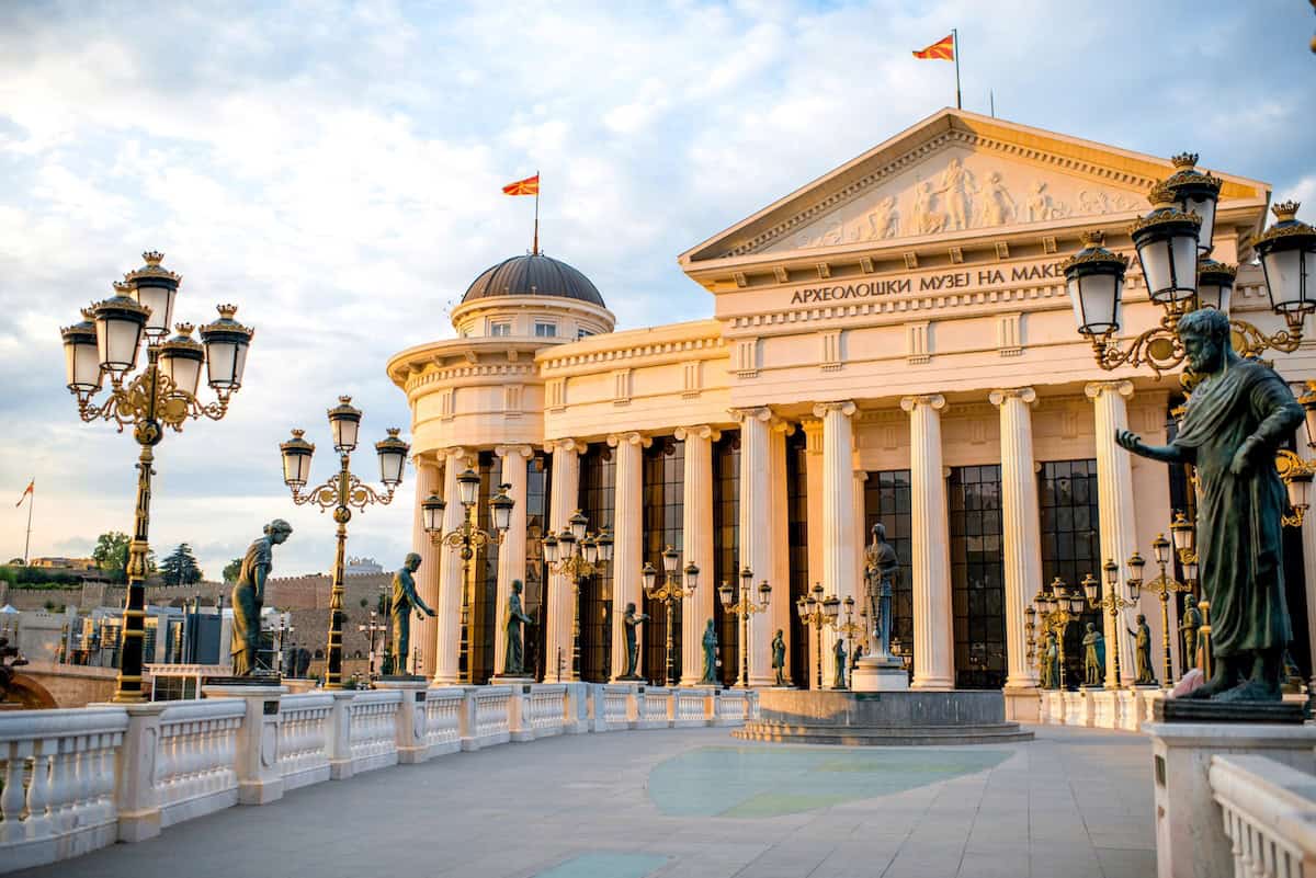 A bridge with lanterns on it leading to a historic looking building in Skopje