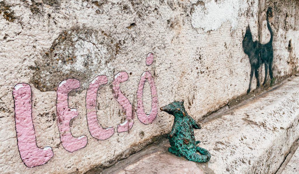 A small statue of a mouse next to a graffiti cat in Budapest