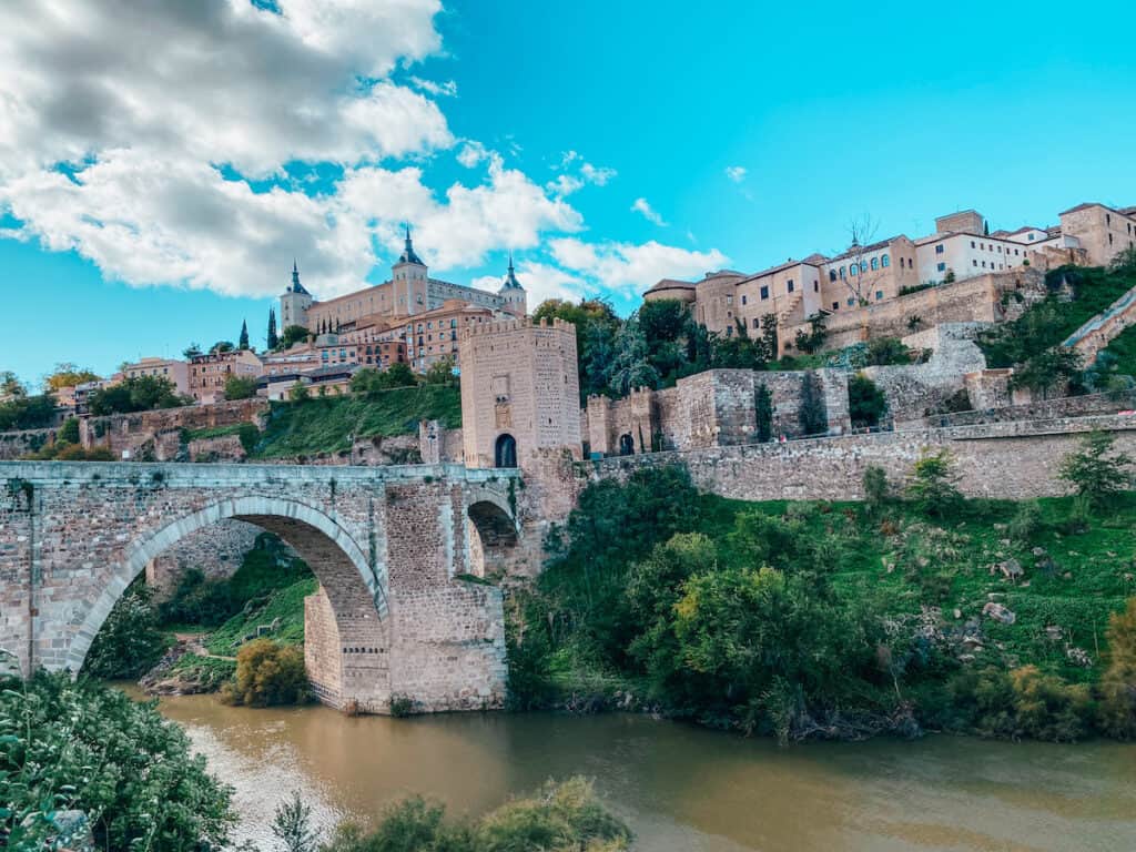 A historic bridge over a river, on the other side of the river is the city of Toledo on top of a hill