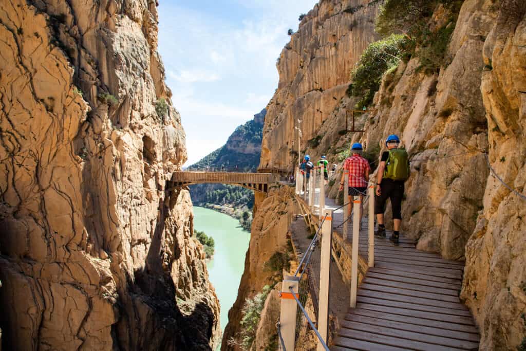 A narrow path right next to a big cliff with a bridge in between a canyon; one of the best day trips from Seville Spain