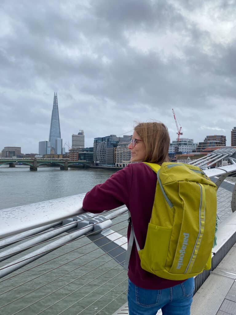 Tina standing on a bridge in London wearing a green Patagonia backpack