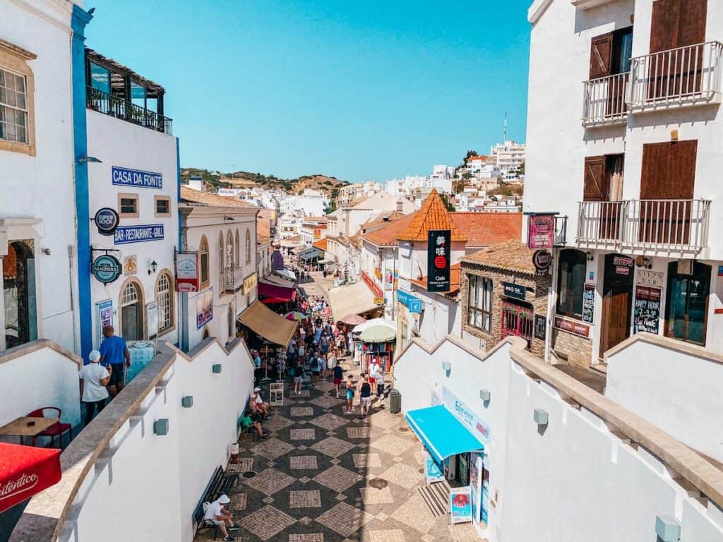 Bustling streets of Albufeira Old Town, thronged with tourists exploring local shops and restaurants, a must-visit for an authentic Albufeira, Portugal experience.