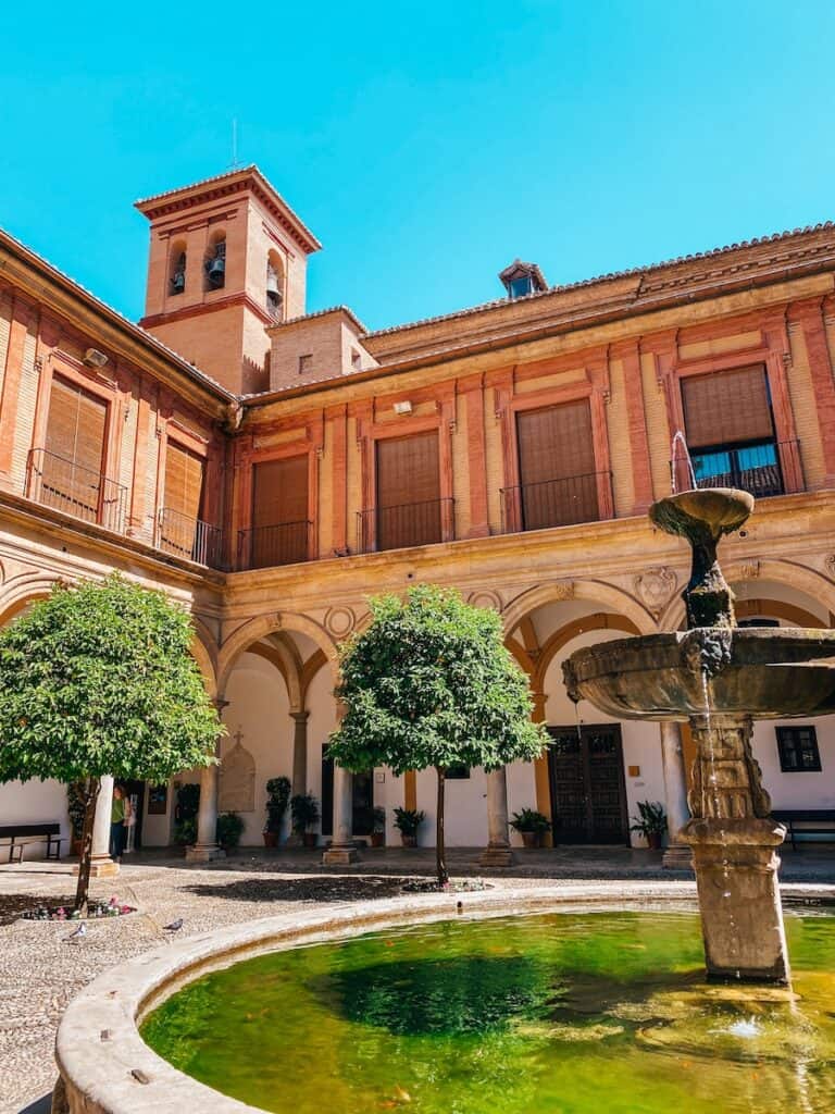 Beautiful courtyard with a central fountain and lush greenery, part of one of the best monasteries in Granada, Spain.