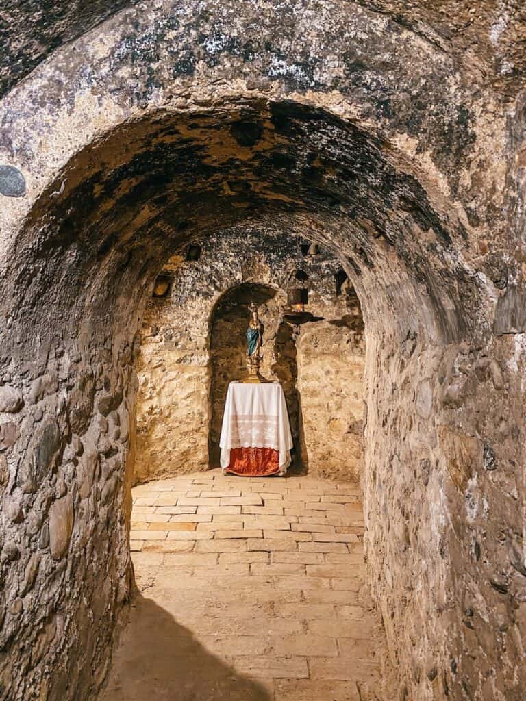 A religious statue in a nook at the end of a cave passage in Sacromonte Abbey.