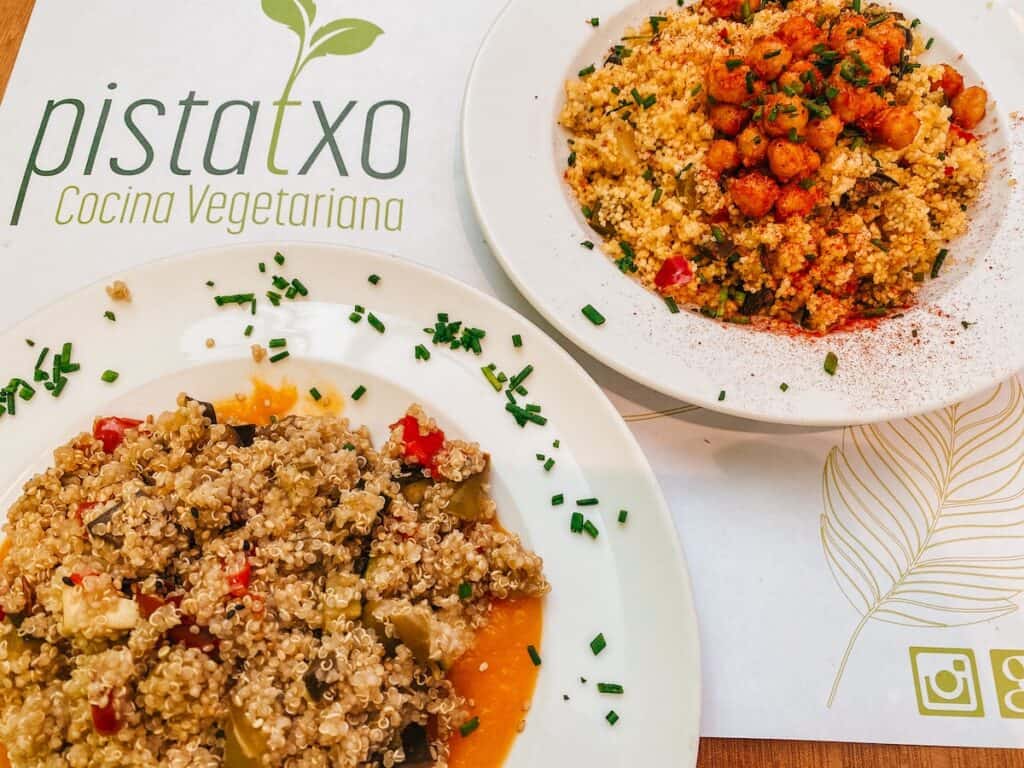 Two plates of vegan food on a paper with Pistatxo written on it, a vegetarian restaurant in Murcia