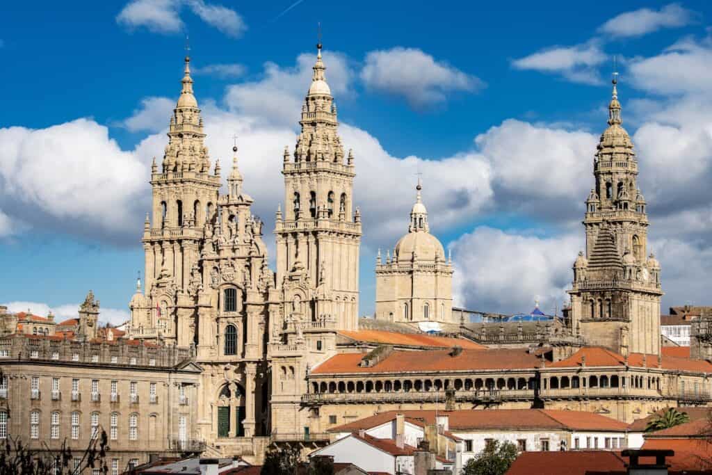 A panoramic view of the Santiago de Compostela Cathedral against a bright blue sky, highlighting its ornate spires and architectural grandeur. This iconic structure serves as the endpoint of the Camino de Santiago.