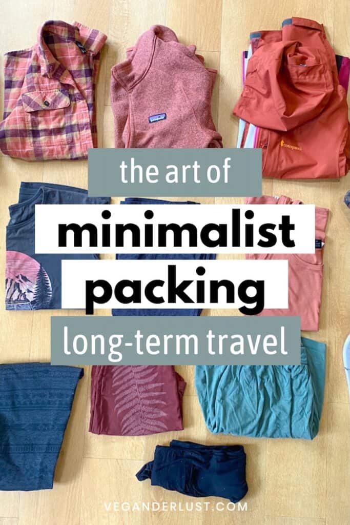 Flat lay of neatly arranged clothing for minimalist long-term travel, featuring items like a flannel shirt, fleece vest, windbreaker, graphic t-shirts, leggings, and shorts in earthy tones. Text overlay reads “the art of minimalist packing long-term travel,” emphasizing lightweight and versatile gear.