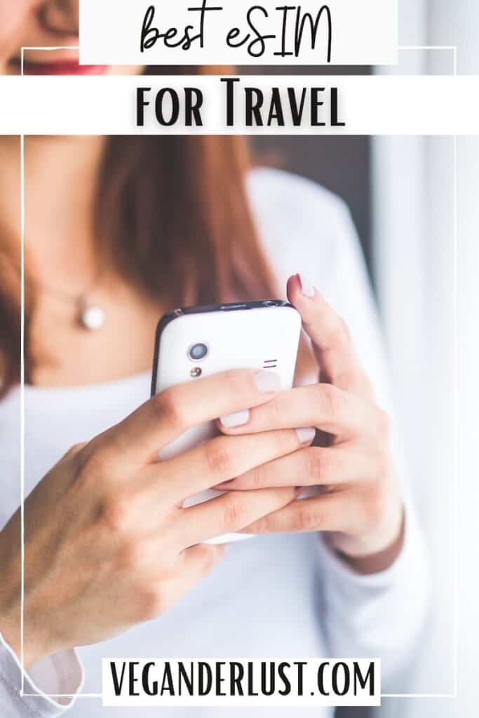 Close-up of a woman using a white smartphone, wearing a white long-sleeve top and a pearl necklace. Text on the image reads “best eSIM for Travel” and “veganderlust.com,” promoting mobile connectivity for travelers.