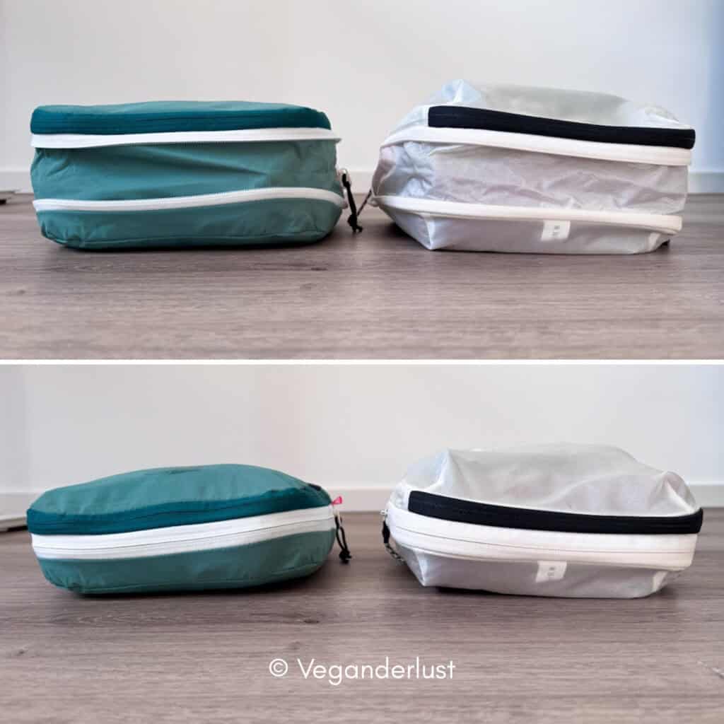 Side by side comparison of two packed travel cubes placed on a wooden floor. The teal cube holds its structured rectangular shape while the light gray cube appears puffier and less compact. This visual highlights differences in compression and overall bulk when packed.