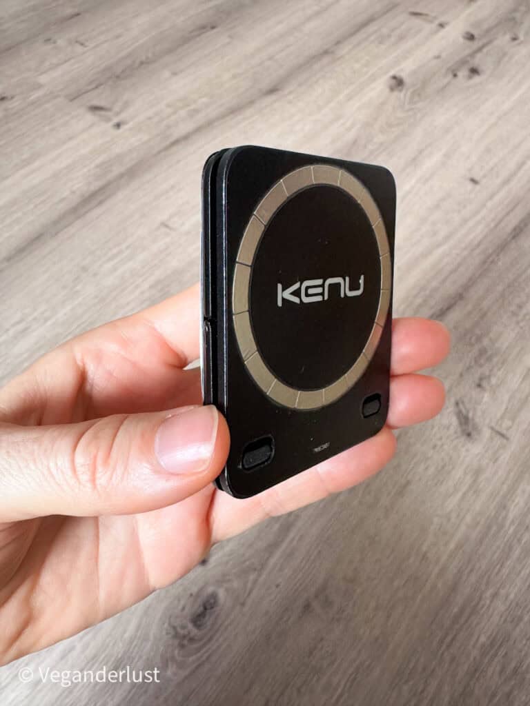 Hand holding a folded Kenu magnetic phone stand in its compact form. The slim square design fits easily in the palm. The image highlights its portability for travel or everyday carry.