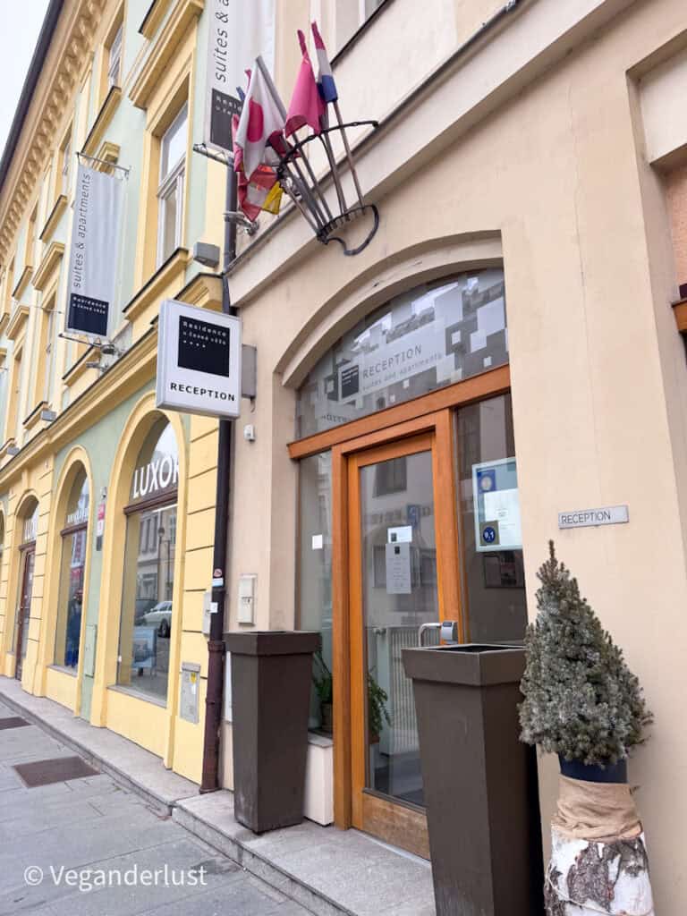 Street entrance to a hotel with signage that reads "RECEPTION suites and apartments" and vertical banners that say "suites & apartments".