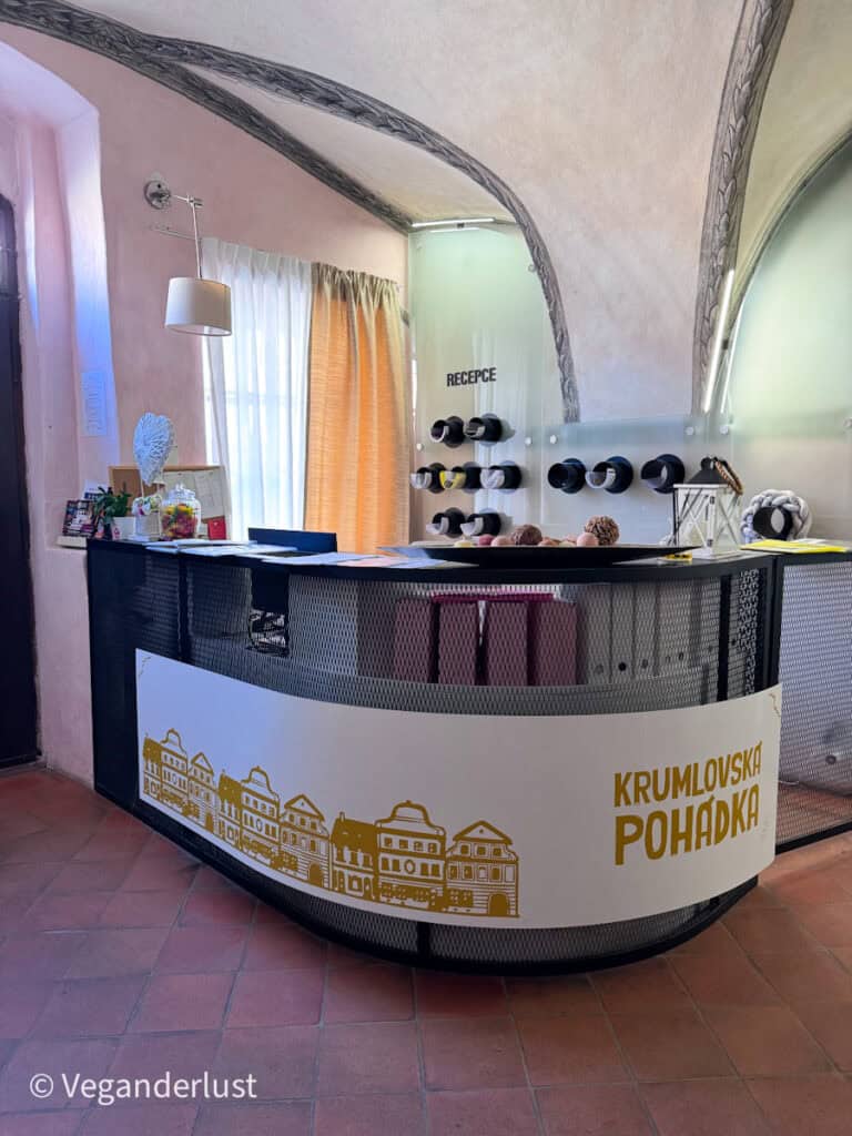Hotel reception desk inside a historic vaulted building with a sign reading "RECEPCE" and the name "KRUMLOVSKÁ POHÁDKA" on the front. Staying in charming historic accommodations like this is part of experiencing things to do in Cesky Krumlov.