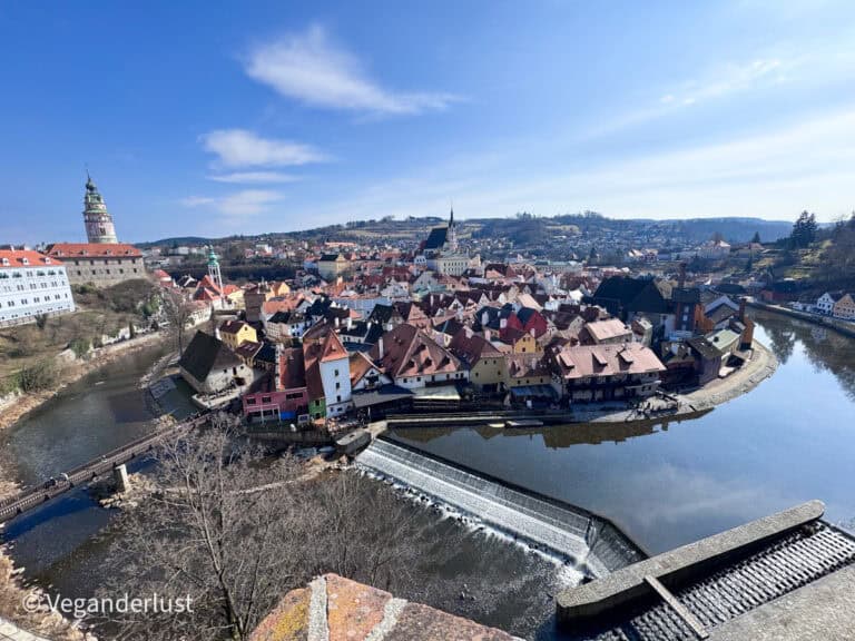 Wide panoramic view of Cesky Krumlov with red rooftops, the winding Vltava River, and the castle tower rising above the historic town. Seeing this iconic view from the castle viewpoint is one of the most breathtaking things to do in Cesky Krumlov.