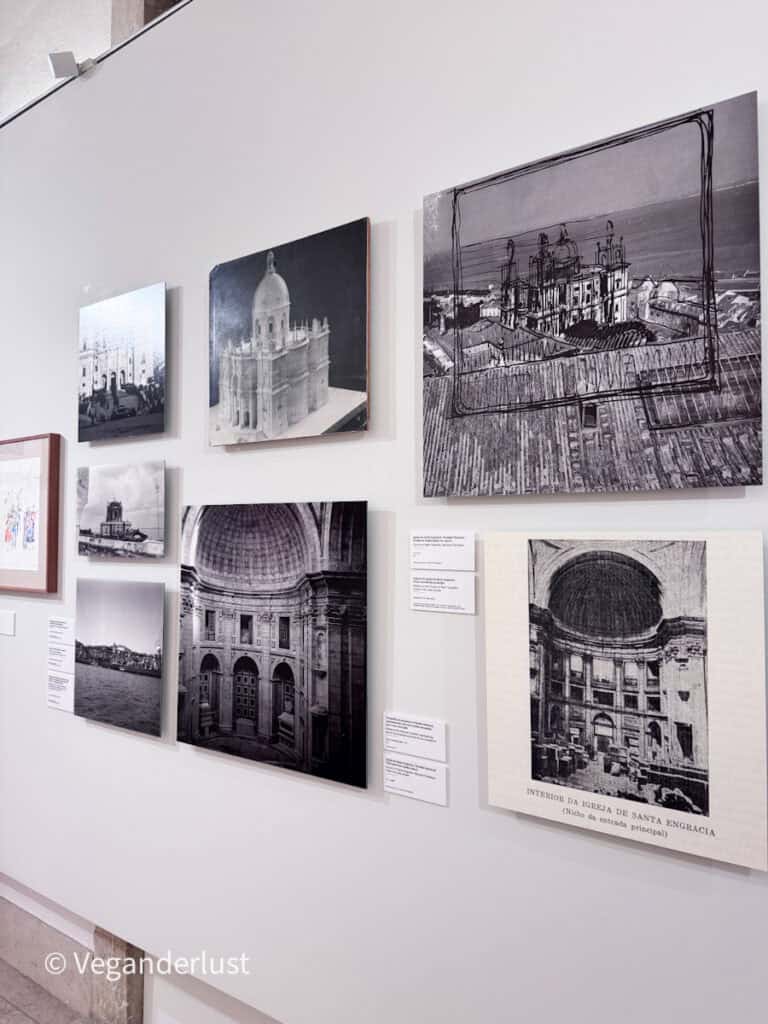 Wall display of framed black and white photos and drawings of a domed church building with small descriptive labels beside them.