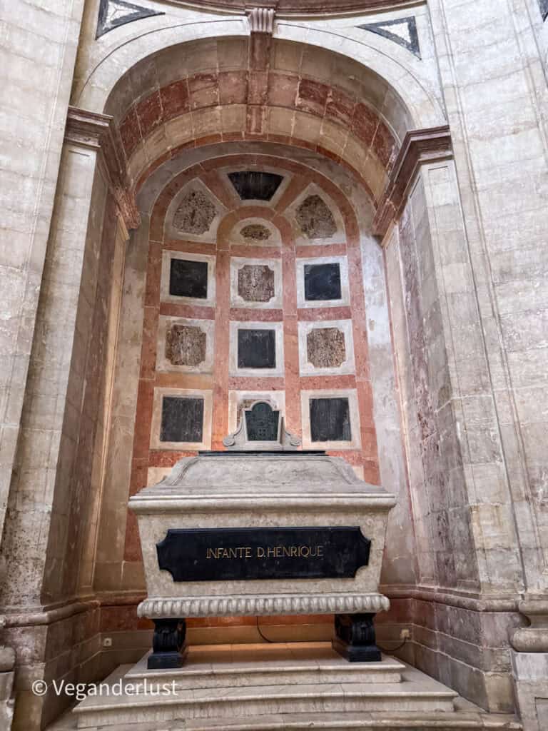 Stone tomb inside a church alcove with text reading "INFANTE D. HENRIQUE" carved on the front.