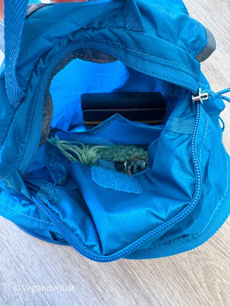 Open blue foldable backpack showing the inside storage compartments and lightweight fabric lining. Small travel items are stored inside the interior pockets of the bag.